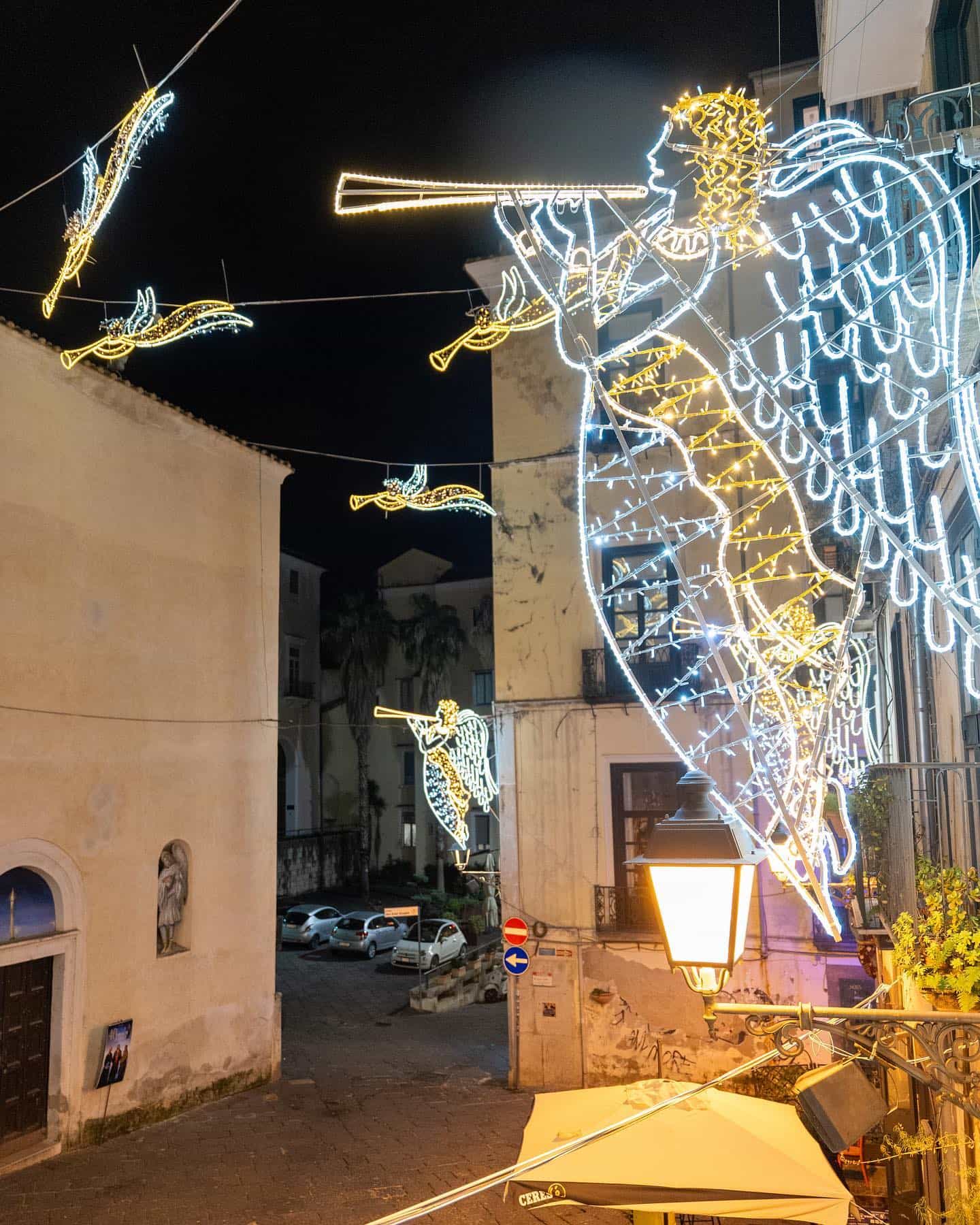 The lit angels of the Luci d'Artista suspended above the street at night