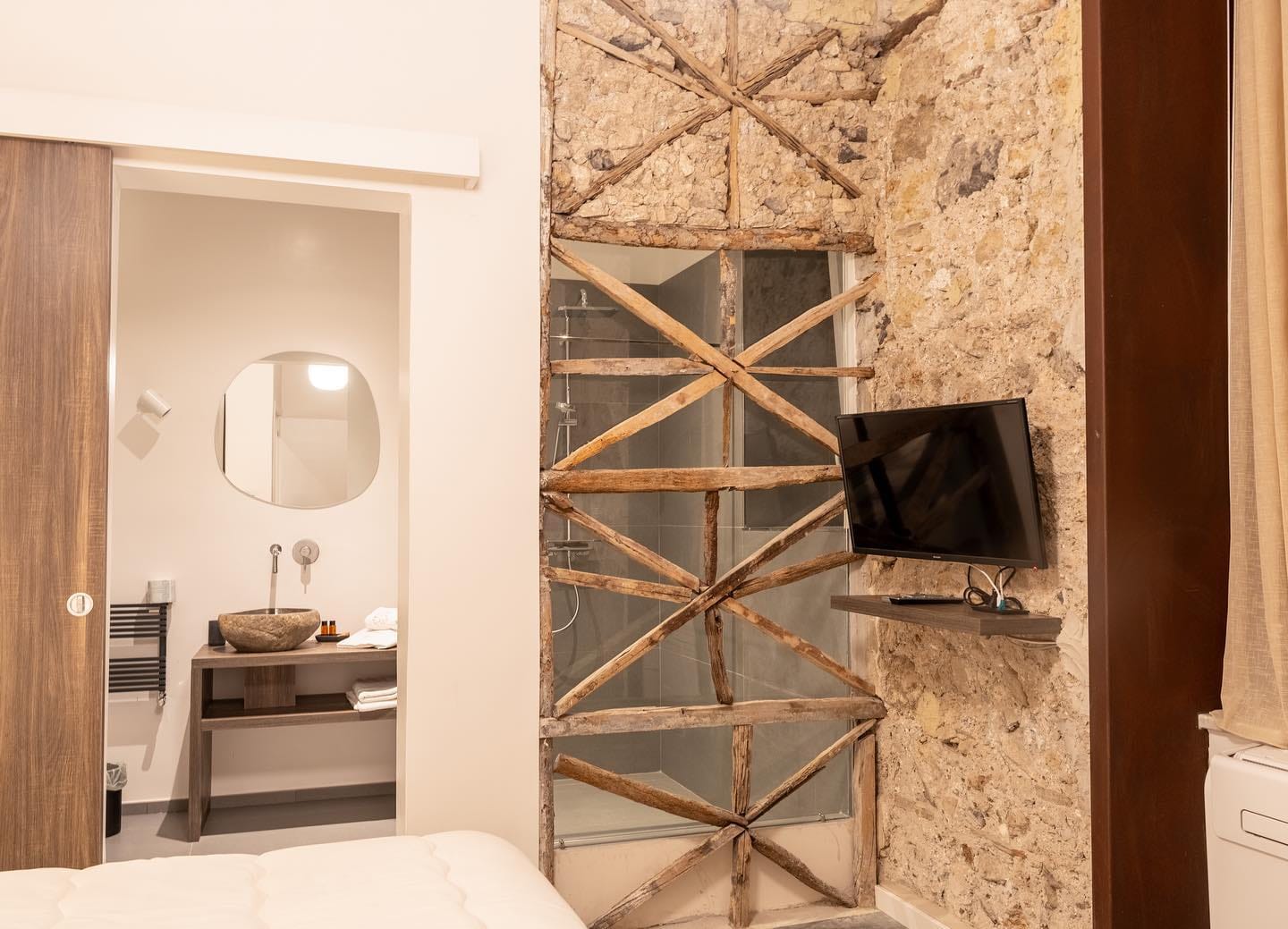 The building's original timber bracing, left visible behind the glass of the shower