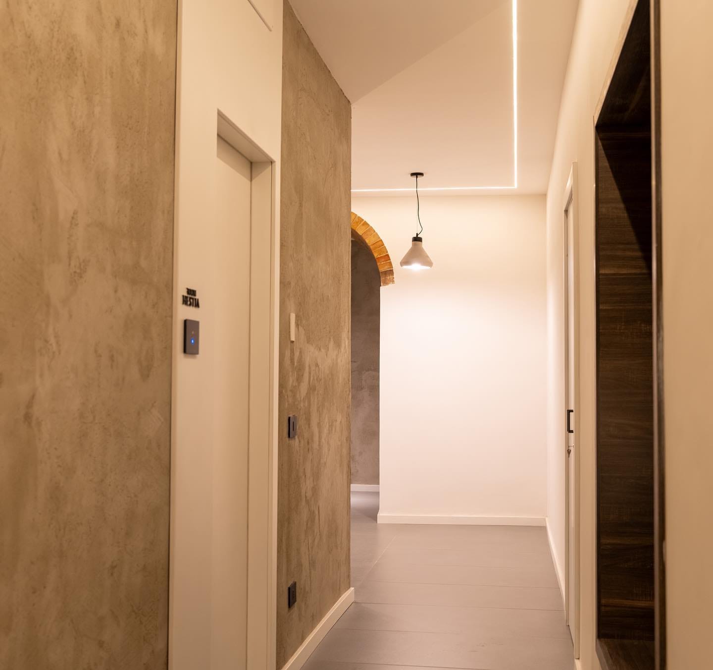 Il corridoio della casa, con l'arco in mattoni a vista e una linea di luce che corre lungo il soffitto