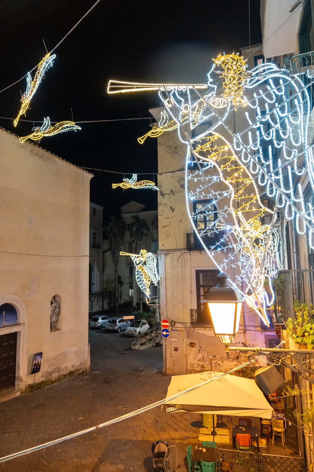 The illuminated angels of the Luci d’Artista hanging over the street, seen from the balcony of Gea