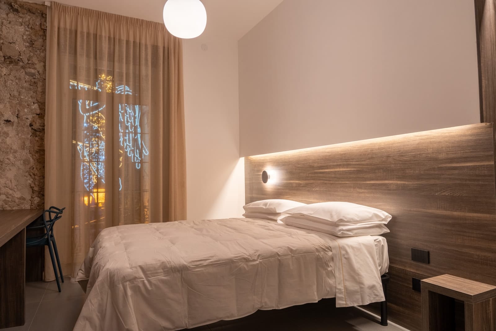 Gea in the evening: the bed, the desk and, behind the curtain, the illuminated angels of the Luci d’Artista