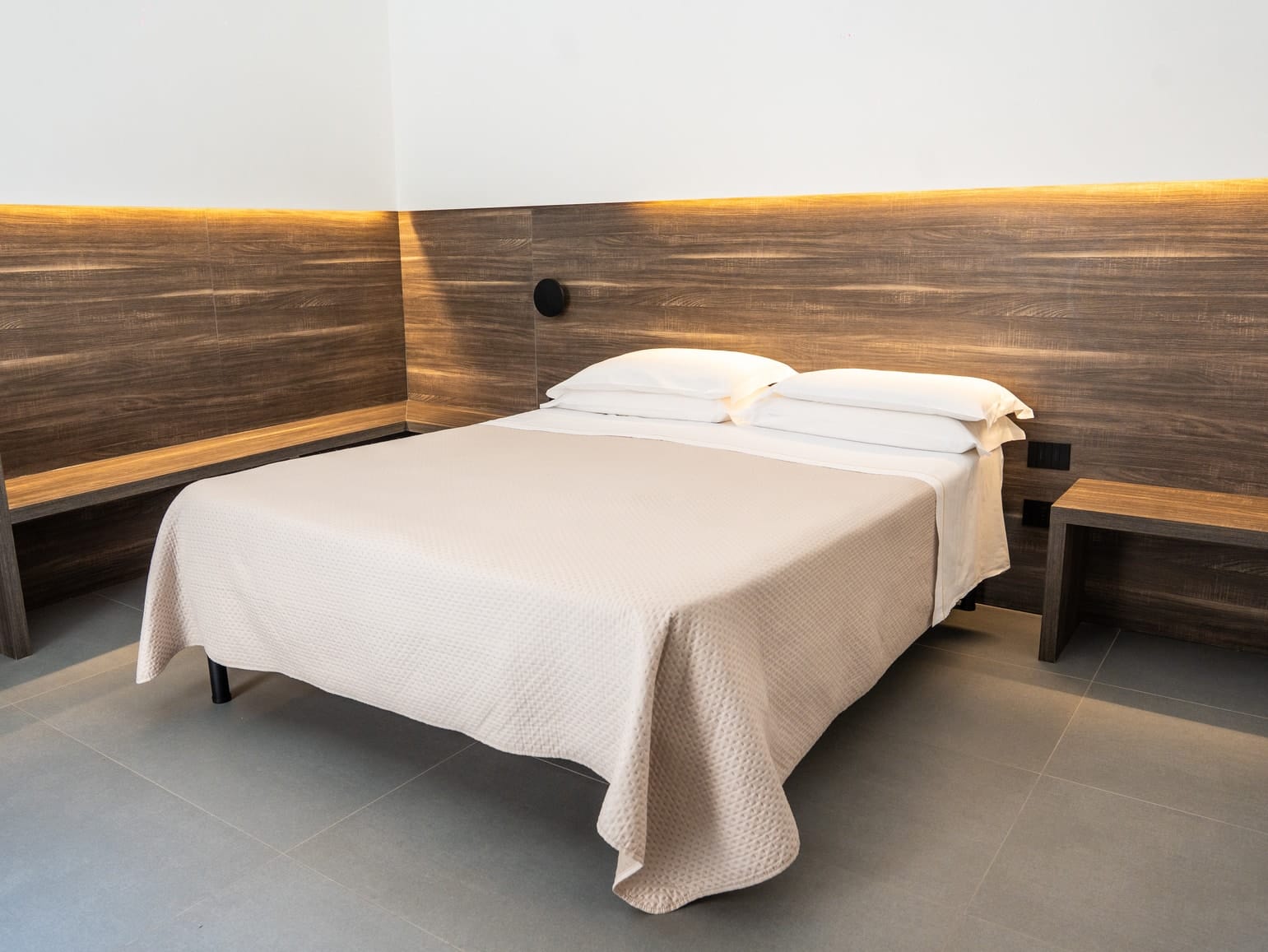 Hera: the bed and the wooden headboard with its hidden light, running along two walls