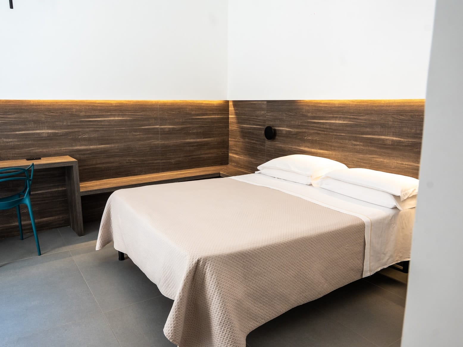The bed in Hera and the desk in the corner, under the wooden headboard that runs along two walls