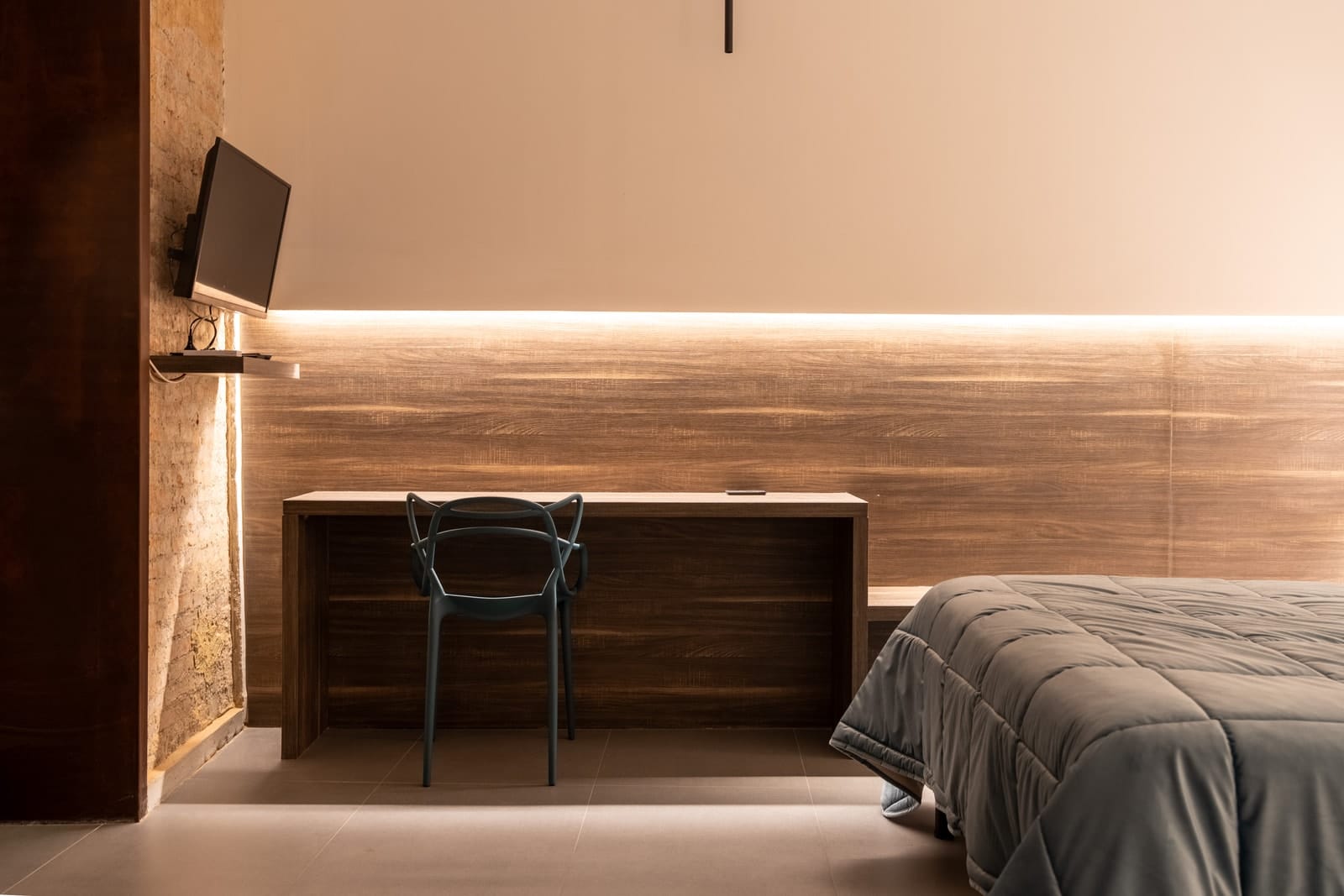 The desk in Hera under the lit headboard, with the television and the bed