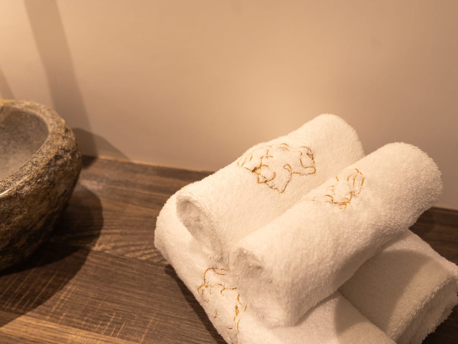 The gold-embroidered towels beside the stone basin, in Hestia
