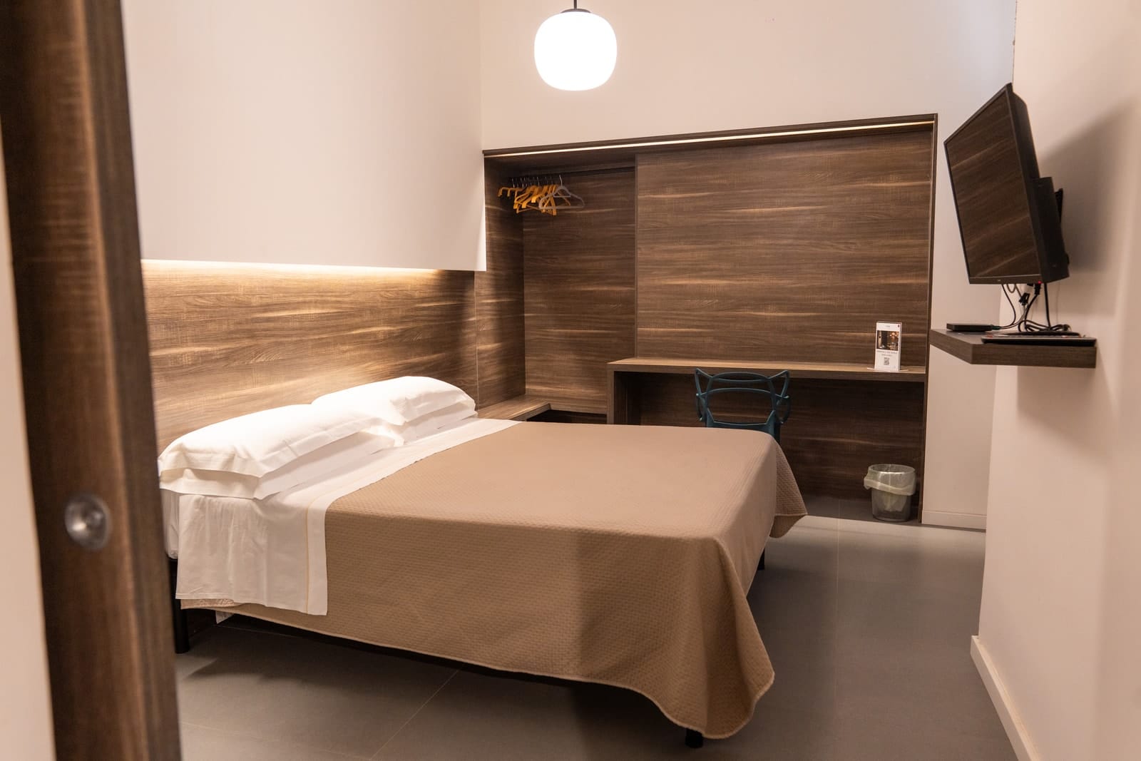 Hestia by day: the bed, the wooden wall with the wardrobe and the desk, the television