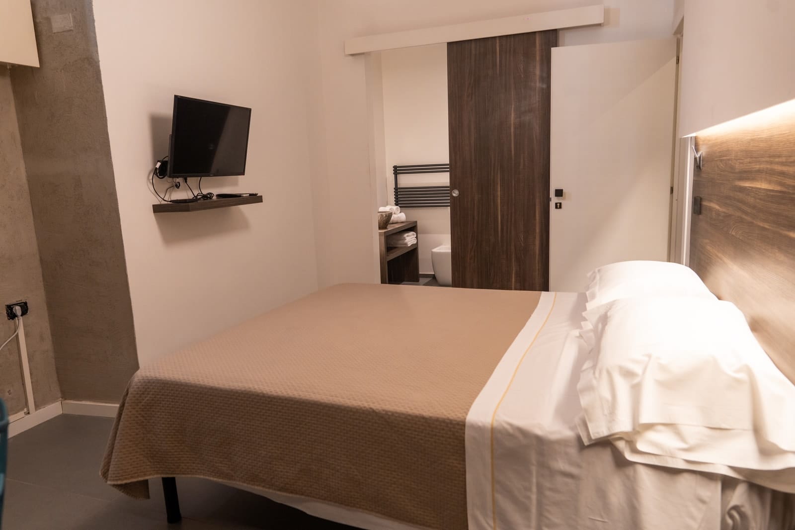 The bed in Hestia, the television and the sliding bathroom door