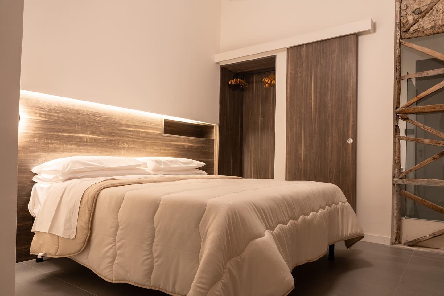 Il letto con la testiera di legno illuminata da dietro